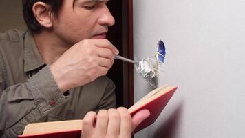 Electrician installing light switch while consulting instruction manual video