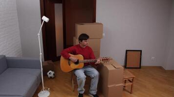 Man playing acoustic guitar in new apartment after moving in video