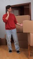 A man talking on a cell phone while standing in a room with boxes video