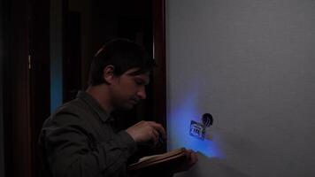 Electrician installing light switch using instruction manual in dark room video