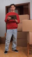 A man standing in a room with boxes and a tablet video