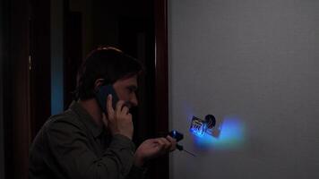 Electrician installing light switch while talking on phone video