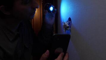 Technician inspecting light switch with uv light and smartphone video