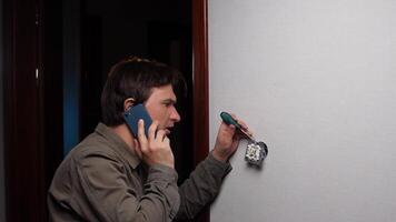 Electrician installing light switch while talking on mobile phone video