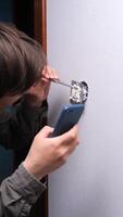 A man is using a cell phone to fix a light switch video