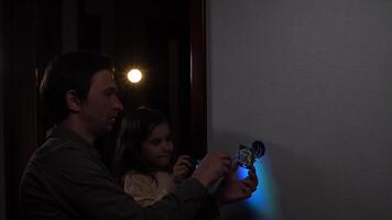 Electrician installing light switch with daughter watching video
