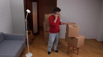 Man talking on smartphone and pointing at cardboard boxes in new apartment video
