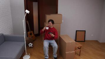 Young man relaxing during home move with coffee video