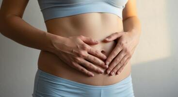 Woman Hands Forming Heart Shape on Abdomen photo
