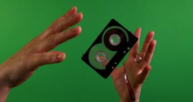 A dynamic VHS tape floating gracefully among hands in front of a vibrant green screen backdrop video