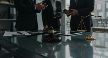 Scales of justice and gavel on a desk with lawyers discussing legal matters photo