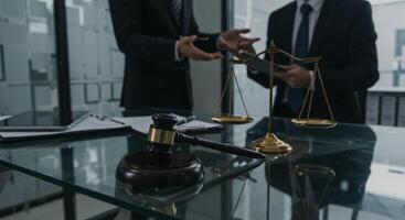 Two men in a law office with scales of justice and a gavel on a glass desk photo