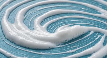 Thick white cleaning foam creating abstract swirls on a textured light blue surface photo