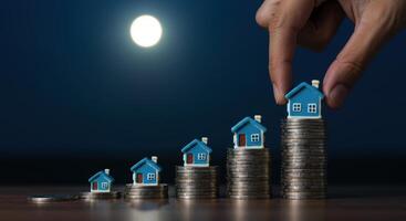 Miniature houses on coin stacks showing real estate investment growth photo