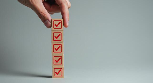 Hand placing checkmark block on a stack representing task completion photo
