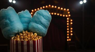 Striped bag filled with caramel popcorn and blue cotton candy at a circus photo