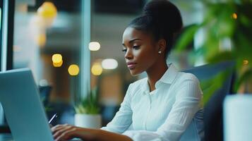 A woman working on a laptop in an office setting. photo