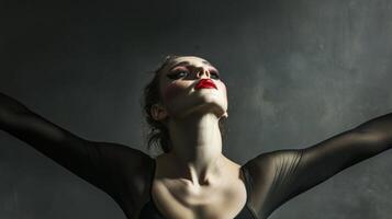 Woman with dramatic makeup and a black outfit posing against a gray background photo