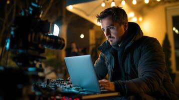 Man Working on a Laptop at Night with a Camera in the Foreground photo