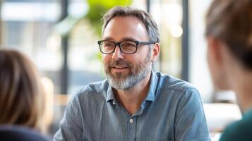Middle-aged man with grey beard and glasses looking to the left, smiling photo