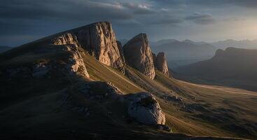 The sun sets over a mountain range with some rocks photo