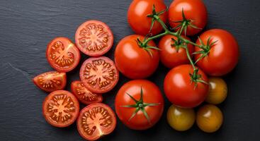 Tomatoes are arranged on a black surface photo