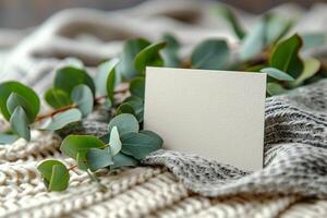 A blank card on a knitted blanket with eucalyptus leaves photo