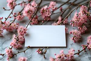 A blank card is placed on a table with pink flowers photo