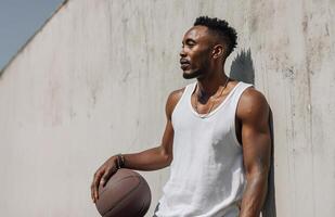 Handsome man leans against wall while playing basketball in sunny outdoor setting photo