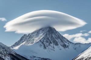 Lenticular cloud gracefully envelops mountain peak under a clear sky showcasing nature's beauty photo