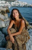 Beautiful woman in leopard-print dress enjoying the golden hour by the sea photo