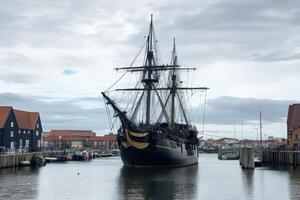Tall ship docks in harbor under clouds photo