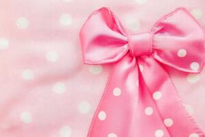 Bright pink bow with white polka dots on fabric photo