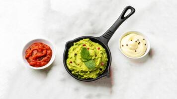Guacamole in a skillet with two small bowls photo