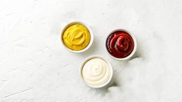 Three bowls of ketchup and mustard on a white background photo