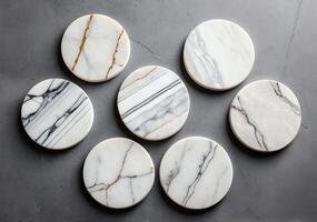 Top view of eight round marble coasters with unique veining patterns arranged on a grey surface photo
