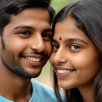 Close-up of a smiling Indian couple with traditional clothing, featuring a young woman with a red bindi and a man with a beard. photo