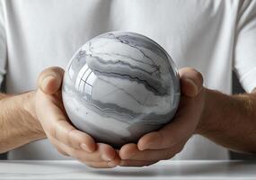 Hands gently holding a polished stone sphere with intricate gray and white marble patterns in 4K photo