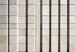 Close-up of a geometric marble wall with vertical and horizontal lines creating a symmetrical pattern in natural light photo