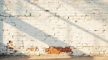 White painted brick wall with shadow and exposed brickwork at the base creates a rustic texture and background for design elements photo