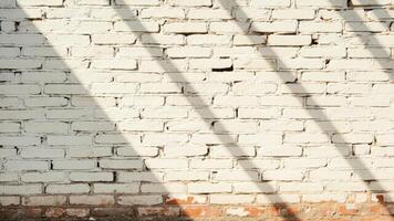 White painted brick wall with diagonal shadow and visible red brick at the bottom a textured architectural background photo