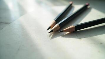 Close up shot of pencils lying on a light background with natural sunlight and shadow photo