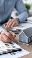 Man with pen and paper at table with model of house photo