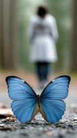 A blue butterfly is sitting on the ground next to a woman photo