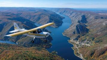 A small airplane flying over a river and mountains photo