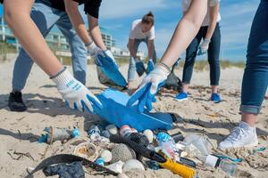 Group of volunteers wearing gloves, picking up plastic and trash from a beach to promote environmental conservation and reduce ocean pollution photo