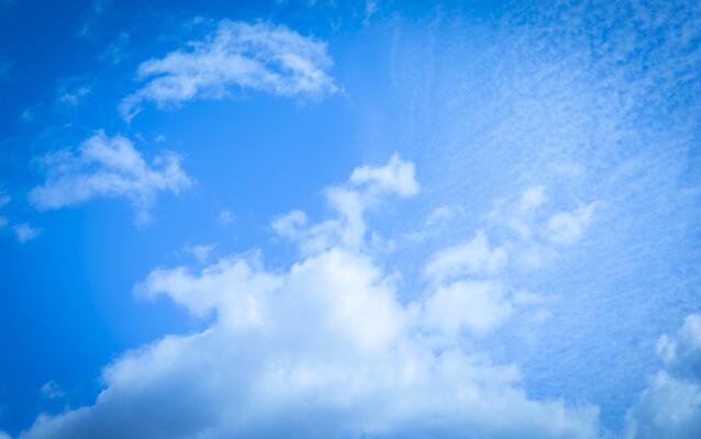 Bright blue sky with fluffy white clouds and soft sunlight shining