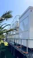 Budva, Montenegro - May 18, 2025. Ferris wheel cabins are folded and arranged on a trailer surrounded by palm trees photo