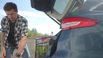 Man loading orange suitcase in car trunk, Packing luggage for travel video