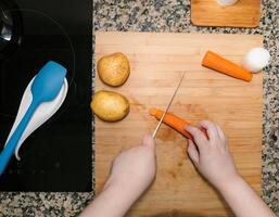 High view of chefs hands preparing and chopping vegetables. Kitchen scenery. Cooking recipe with ingredients around. Home made plate. photo